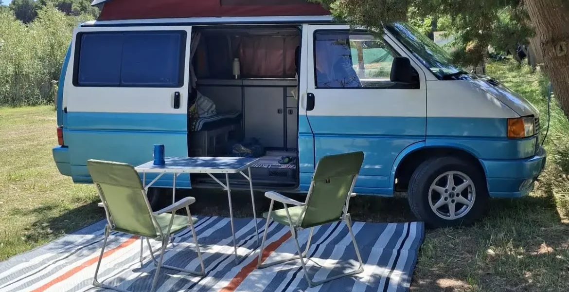 Van camperizzato vintage azzurro e bianco in campeggio